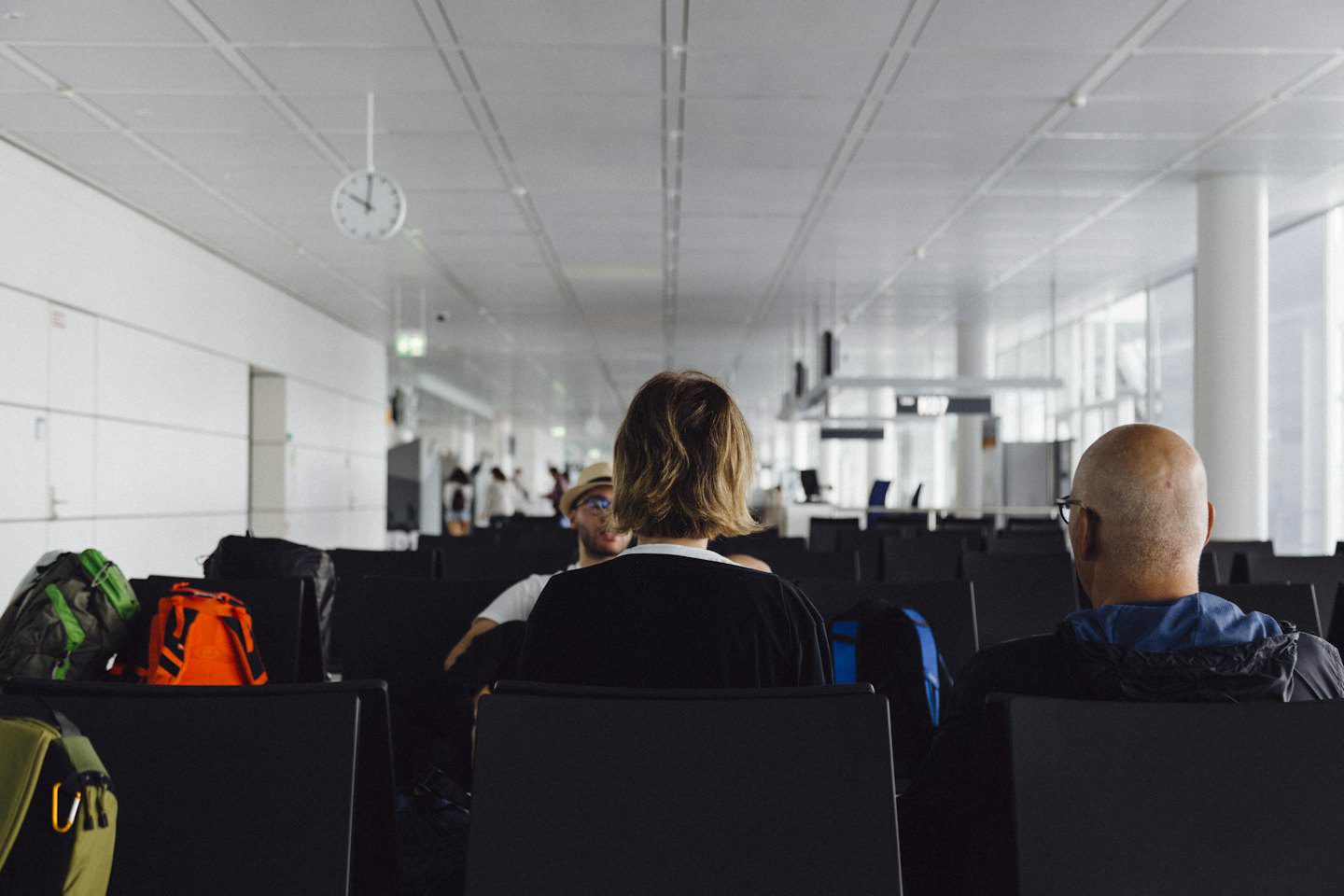 Viajeros esperan con su equipaje en una sala de aeropuerto moderna.