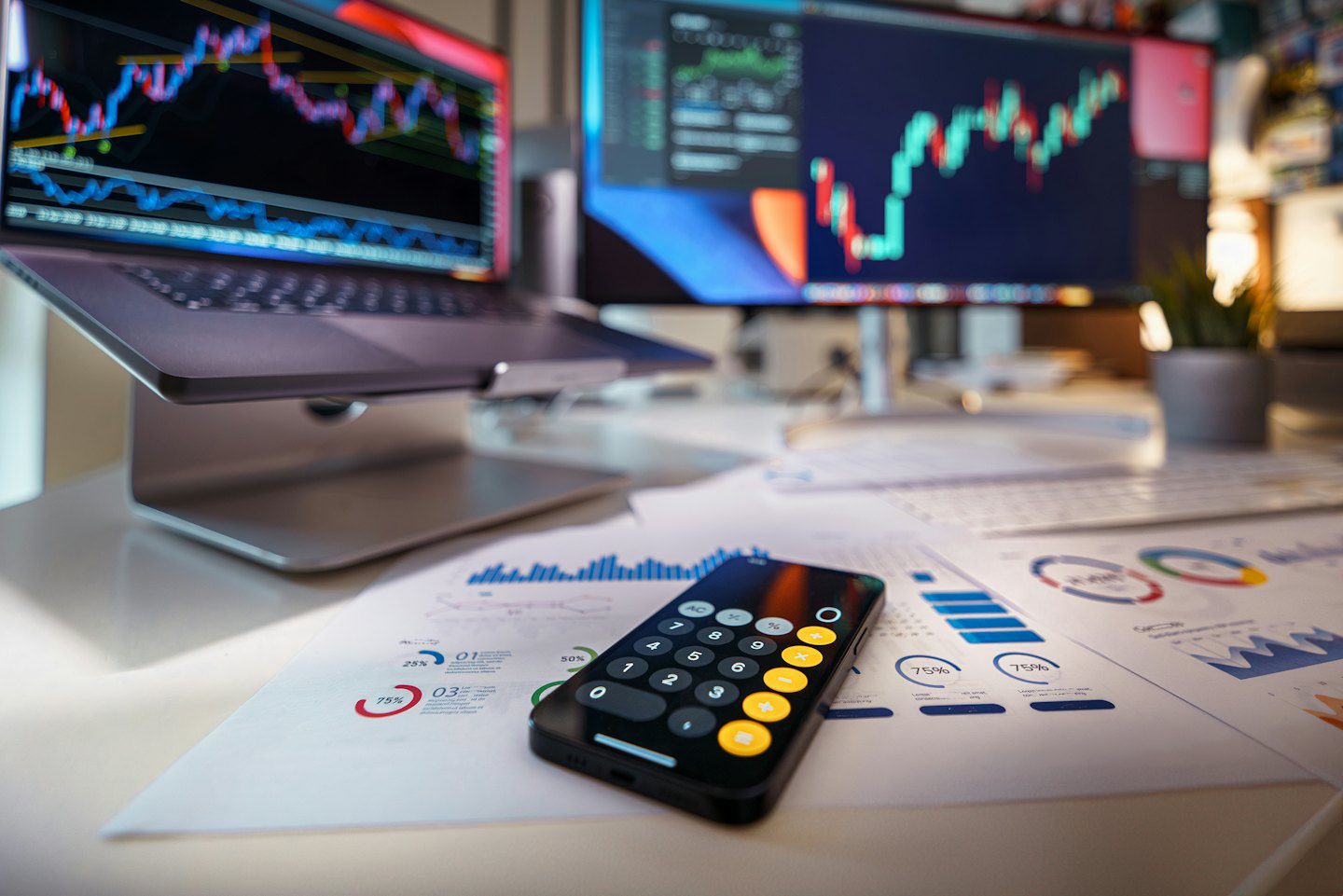 Portátil y smartphone sobre un escritorio mostrando gráficos y datos financieros.
