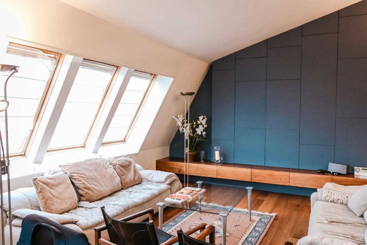 Sala de estar moderna con pared de acento azul y ventanas de tragaluz.